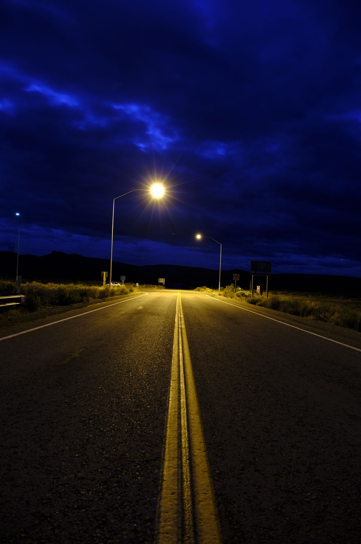 Empty highway at night under a glowing streetlight