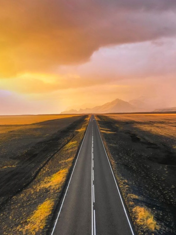 Empty open highway disappearing to the horizon under a dramatic sunset sky